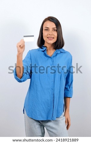 Cute brunette woman wearing a stylish blue shirt showing a plastic card mockup.