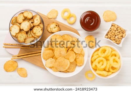 Various unhealthy snacks on wooden background, top view