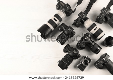 Modern cameras on white wooden table, flat lay. Space for text