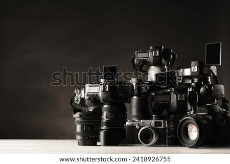 Modern cameras on white wooden table against dark background. Space for text