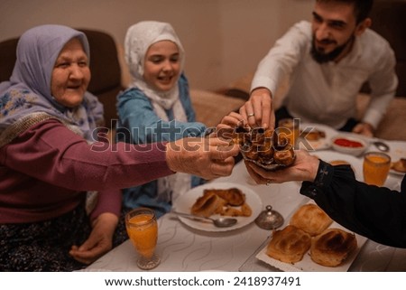 Happy Muslim family having iftar dinner to break fasting during Ramadan dining table at home. High quality photo Royalty-Free Stock Photo #2418937491