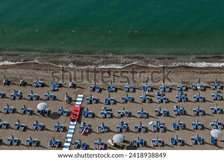 Amalfi Sea Coast with Umbrellas, people swim, and Yachts. Clean and blue sea where to swim. Photo for tourism and summer background. Concept of vacation and beach life in the open air  