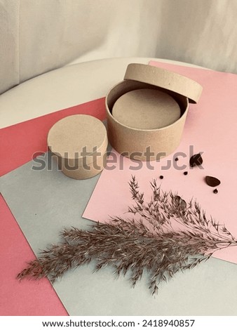 Three small kraft gift boxes of different sizes with dried decorations on colored paper. One of the boxes is inside a larger box 