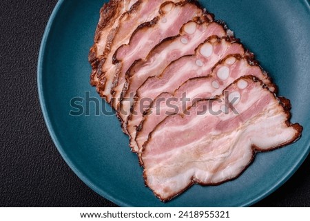 Delicious fresh pancetta or bacon with salt and spices cut into thin slices on a dark concrete background