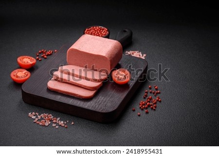 Delicious canned pink ham with salt, spices and herbs on a dark concrete background Royalty-Free Stock Photo #2418955431