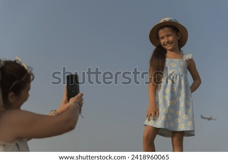 Daughter posing for a photo that her mother takes with a cell phone