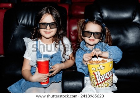 Little girls, friends or sisters in 3d glasses watching a cartoon film at a movie theater, house or cinema. Look expressive and emotional. Sitting alone and having fun. Friendship, family, childhood
