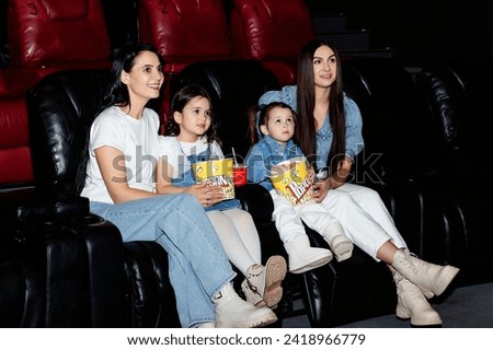 Little girls, friends with their moms watching a cartoon film at a movie theater, house or cinema. Look expressive and emotional. Sitting alone and having fun. Friendship, family, childhood