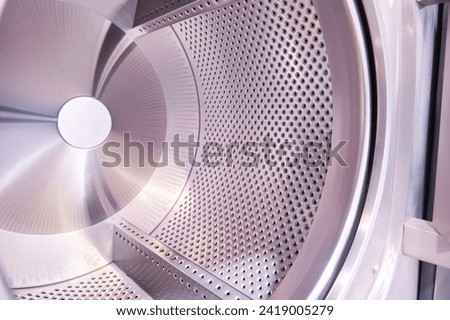 Interior of an industrial washing machine with the door open revealing the washing drum. Laundry service concept. Royalty-Free Stock Photo #2419005279
