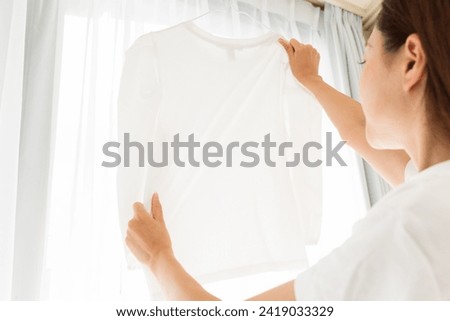 A clean routine of stretching and drying a plain white T-shirt. Royalty-Free Stock Photo #2419033329