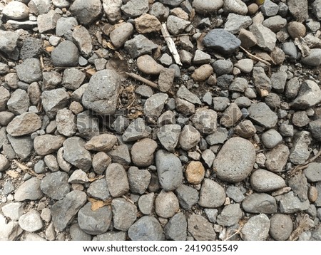 A photo of a background of neatly arranged pebble stones right on the side of the road