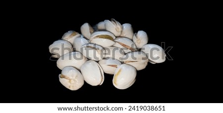 Freshly baked pistachios on a black backdrop. Perfect for food blogs and wellness content. Irresistible and versatile stock photo.