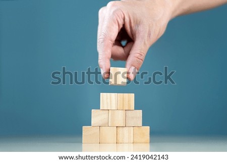Blank wooden cubes with copy space for user-input text and an infographic icon are manually placed and stacked on a table.