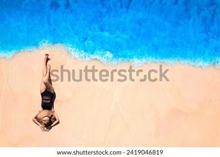 Aerial view of woman lounging on the beach for summer vacation concept. Nature of the beach and sea Summertime with sunshine, sandy beaches, and sparkling sea water.