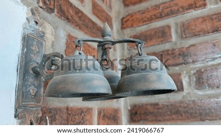 Abstract, not focus. Photo of a house bell-shaped bell made of copper with Red brick background.