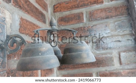 Abstract, not focus. Photo of a house bell-shaped bell made of copper with Red brick background.