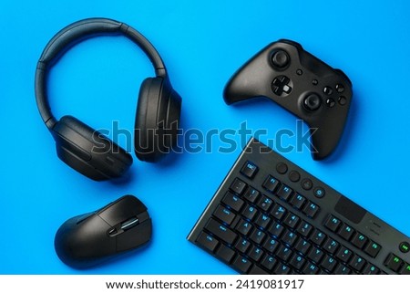 Top view of gamer table with computer keyboard, joystick and headphones