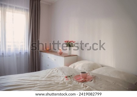 pink cup of coffee on bed with flowers in vase  in white bedroom Royalty-Free Stock Photo #2419082799
