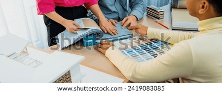 Skilled interior design team carefully selecting curtain materials while coworker selecting the color of curtain with house model placed on meeting table. Creative design concept. Variegated. Royalty-Free Stock Photo #2419083085