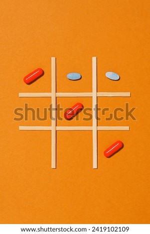 Tic tac toe game with medical pills on orange background, directly above shot Royalty-Free Stock Photo #2419102109