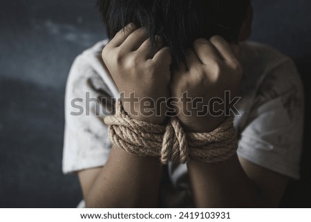 Victim boy with hands tied up with rope in emotional stress and pain,  kidnapped, abused, hostage,  afraid, restricted, Stop violence against children and trafficking Concept. Royalty-Free Stock Photo #2419103931