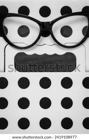 50's frame glasses on a plastic stool, forming an expression of terror.
