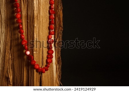 Red coral necklace on a wooden surface. Dark background with blank space for text.  Royalty-Free Stock Photo #2419124929