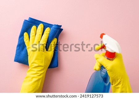 Ultimate home cleaning solution. First person top view of hands in protective gloves, utilizing a spray bottle and a microfiber cloth for windows, against gentle pink background with space for copy