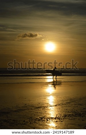 Surfer walking on sunset beach