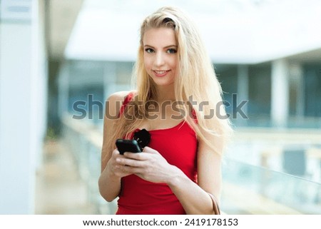 Smiling young woman using her phone in a modern building