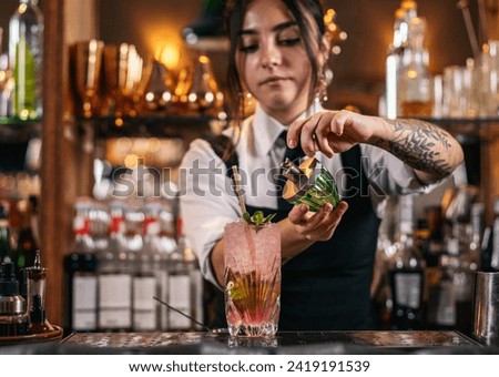 Female bartender preparing a mojito cocktail served in a tall glass in a traditional cocktail bar Royalty-Free Stock Photo #2419191539