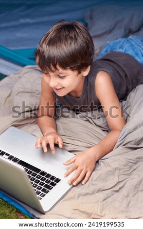 Kid, relax and laptop to watch cartoon, movie or online games for holiday or vacation. Child, smile and play video with computer on website, streaming or search on internet for elearning with media