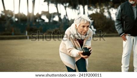 Senior woman, bowling and park on grass for sport, fitness and games for competition, health or fun. Elderly people, metal ball and lawn for contest, funny laugh or workout with blowing for good luck