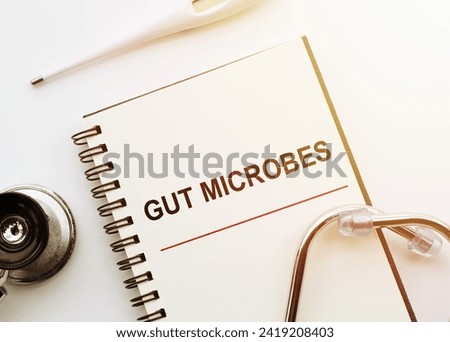 GUT MICROBES phrase on a notepad with a stethoscope and electronic thermometre on white doctor table. Royalty-Free Stock Photo #2419208403
