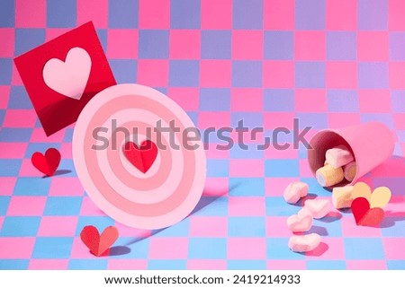 Cute paper cut in heart shape and bullseye decorated with sweet marshmallow on pink and purple checkered background. Ideas for design valentine’s day