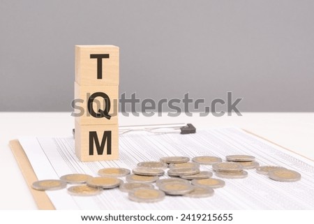 wooden cubes on a brown background with the text TQM - an abbreviation for Total Quality Management. strong business concept Royalty-Free Stock Photo #2419215655