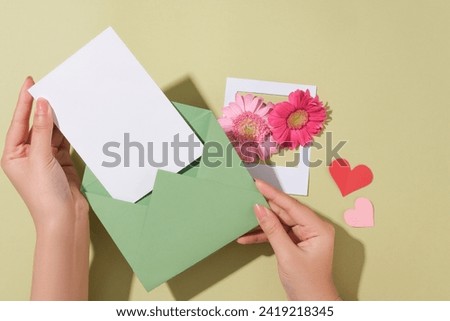 The model prepares to put the white card with copy space in the envelope. A paper picture frame decorated with flowers and hearts. Content about International Women’s Day can be added to copy space