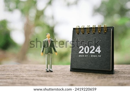 close up 2024 small calendar and businessman miniature on wood table, copy space for text, planning and manage to success business concept