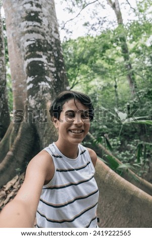 Teenage girl taking a selfie next to a big tree, adventure in the Peruvian Amazon