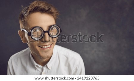 Closeup studio portrait of funny nerd wearing retro vintage thick rimmed glasses on copyspace background. Happy young man in uncool old-fashioned round frame spectacles looking at camera and smiling