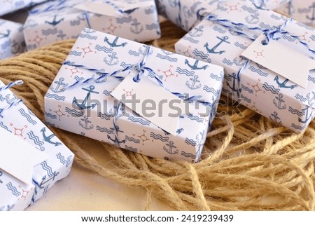 Wedding favors nautical style decoration soap box guest gifts, wrapped in blue white anchor pattern paper, ribbon, custom label, sailor rope background, original summer beach party souvenir Royalty-Free Stock Photo #2419239439