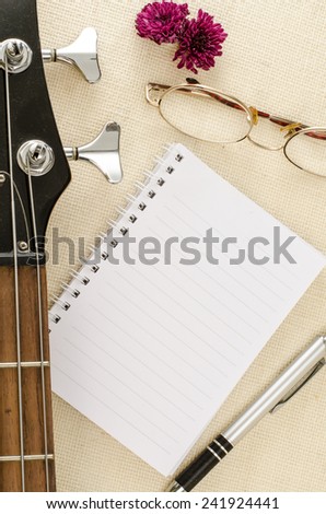 Blank paper with pen on electric bass guitar on brown sack background