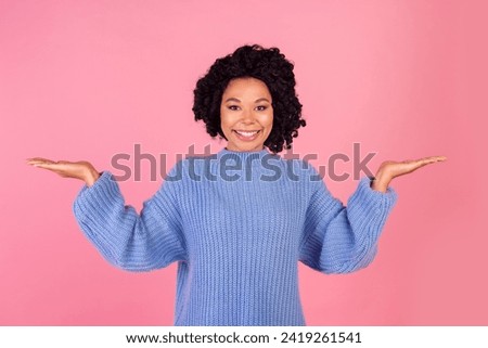 Photo portrait of attractive young woman hold compare empty space dressed stylish blue knitwear clothes isolated on pink color background