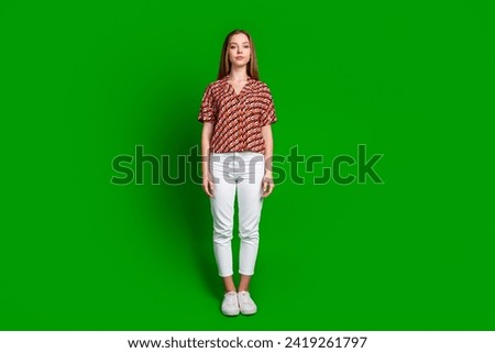 Full size photo of friendly nice lovely teen girl wear print blouse white trousers standing isolated on vibrant green color background