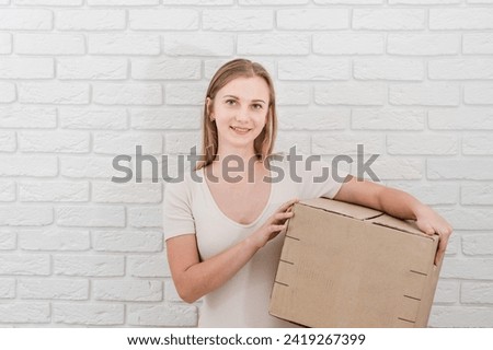 Pretty woman holding cardboard box. Delivering a parcel
