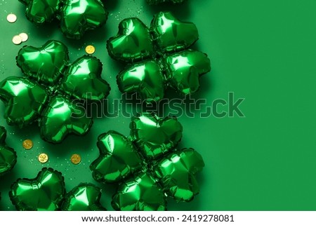 Balloons in shape of clover and coins on green background. St. Patrick's Day celebration