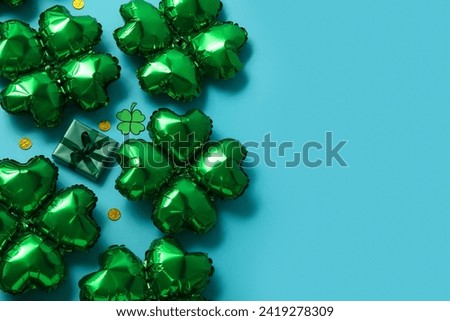 Balloons in shape of clover and decorations for St. Patrick's Day celebration on blue background