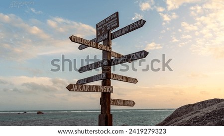 A directional sign reading "Tapak Natuna" (Natuna Site) on a rocky beach in Natuna, Indonesia