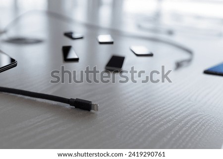 Smartphone gadget free charging station at public place, A row of smartphones plugged in and charging at a public charging hub Royalty-Free Stock Photo #2419290761