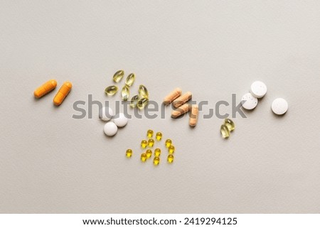 Groups of colored and different shaped pills, meds, capsules, tablets, vitamins, minerals and food supplements on light grey background top view.